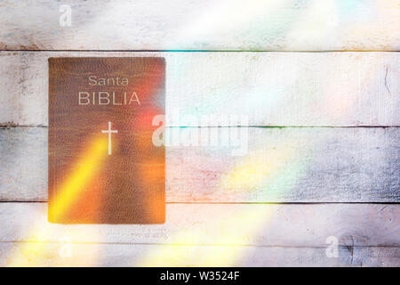 Version espagnole de la Sainte Bible avec certains vitraux réflexion sur une table en bois. Vue de dessus et copie vide de l'espace pour l'éditeur de texte. Banque D'Images