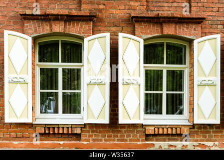 Deux fenêtres avec l'architrave en bois sculpté dans la vieille maison en bois dans la vieille ville russe. Banque D'Images