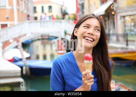 Femme à Venise, Italie la consommation de crème glacée en vacances voyage. Smiling happy mixed race woman asiatiques ayant du plaisir de manger des aliments glace italienne en plein air pendant les vacances à Venise, Italie, Europe. Banque D'Images