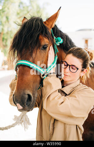 Jeune femme kinésithérapeute en prenant soin d'un cheval brun. Banque D'Images