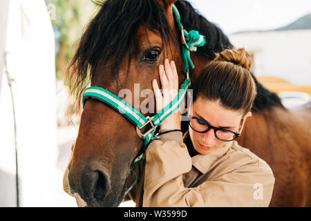 Jeune femme kinésithérapeute en prenant soin d'un cheval brun. Banque D'Images