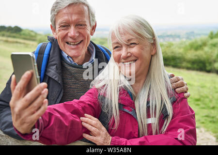 Happy Senior Couple Hiking in Countryside debout près de la porte et en tenant le téléphone mobile Selfies Banque D'Images