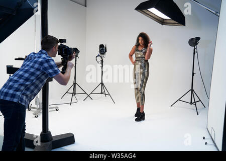 Photographe travaillant avec des photos de mode sur modèle en Studio Banque D'Images