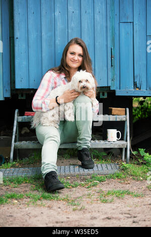 Portrait de jeune femme brune assis dehors avec son petit chien Banque D'Images