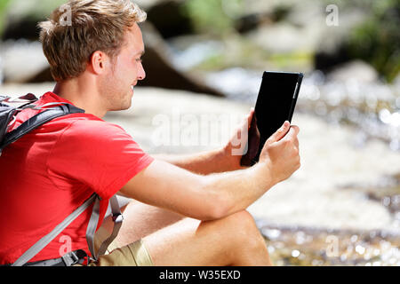 Ordinateur tablette randonneur homme randonnée dans le Yosemite, USA en utilisant app voyage ou carte pendant la randonnée, le repos par la rivière. Caucasian male hiker relaxing un jour d'été. Banque D'Images