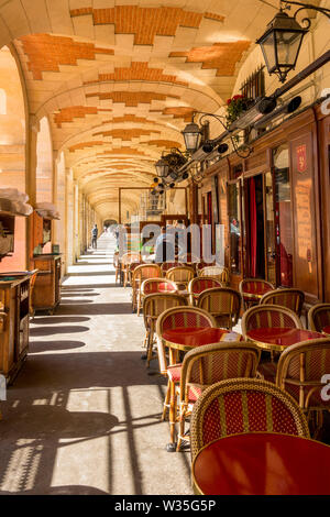 Café terrasse avec tables et chaises, sous les arcades de la Place des Vosges, Paris, France. Banque D'Images