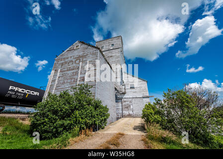 Pennant, SK/Canada- 9 juillet 2019 : l'élévateur à grain vintage abandonnés Battrum (Saskatchewan) avec un train à côté d'elle Banque D'Images