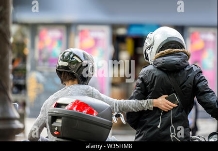 Un homme et une femme portant des casques de protection avec les adaptateurs sont voyageant sur une moto et arrêté dans la rue Ville de clarifier la route de trav Banque D'Images
