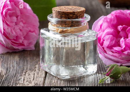 Une bouteille d'huile essentielle de Rose de mai des fleurs sur une table en bois Banque D'Images