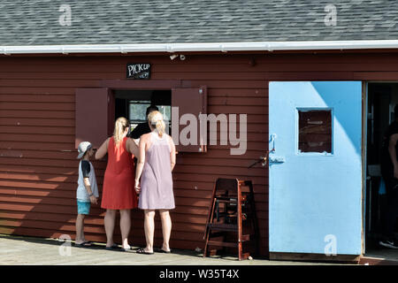 Clients viennent chercher leur repas de homard sur le quai de cinq îles Société Homard dans cinq îles Harbour, Georgetown, Maine. Banque D'Images