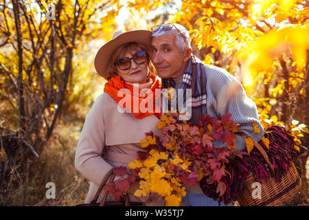 Couple en forêt d'automne. Middle-aged man and woman hugging et de refroidissement à l'extérieur. Panier pique-nique pour les personnes titulaires Banque D'Images