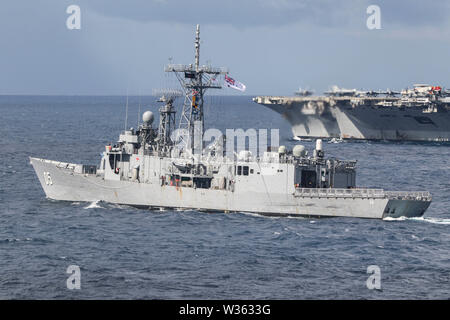 190711-N-DX072-1070 mer de Tasmanie (11 juillet 2019) La Marine royale australienne de la classe Adélaïde frégate lance-missiles HMAS Melbourne (FFG 05), gauche, et de la marine de classe Nimitz porte-avions USS Ronald Reagan (CVN 76), transport en commun avec le dock de transport amphibie USS Green Bay (LPD 20) dans une photo de l'exercice (PHOTOEX) durant 2019 Sabre Talisman. Green Bay, partie de la Guêpe, avec groupe expéditionnaire lancé 31e Marine Expeditionary Unit, participe actuellement à Talisman Saber 2019 au large de la côte nord de l'Australie. Un accord bilatéral, événement biennal, Talisman Sabre est conçu pour améliorer l'U Banque D'Images