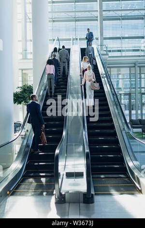 Les gens d'affaires diversifié à l'aide d'escalators in modern office Banque D'Images