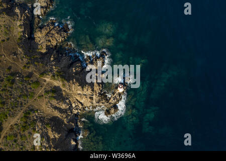 Vue de dessus, superbe vue aérienne d'une vieille et belle plage situé sur une côte rocheuse baignée par une mer agitée. Faro di Capo Ferro. Banque D'Images