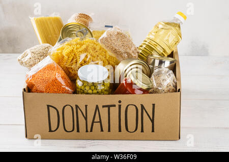 Donation box avec divers aliments. Ouvrir boîte en carton avec de l'huile, de la nourriture en conserve, céréales et pâtes alimentaires. Banque D'Images