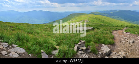 Vue panoramique à partir de Pikuy monter sur la vallée et la route entre green mountain majestueux de collines couvertes de forêts luxuriantes et de l'herbe verte. Nuageux jour d'été. Banque D'Images