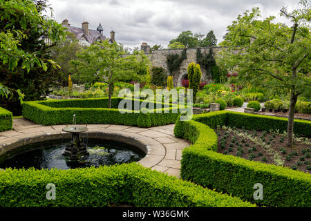 Fort bien clipsé haies entourant une petite piscine avec fontaine à jardins Bodnant, Conwy, Pays de Galles, Royaume-Uni Banque D'Images