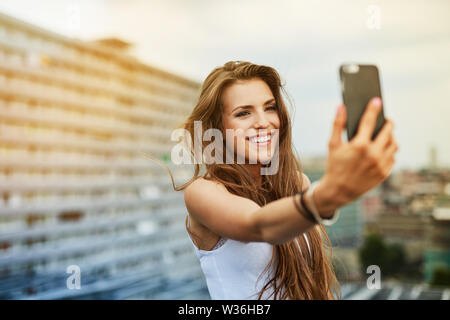 Happy young woman taking sur rootfop selfies Banque D'Images