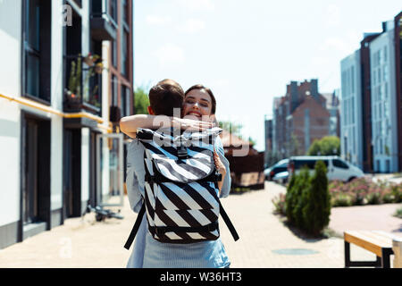 Transmission d'épouse hugging her man wearing backpack Banque D'Images