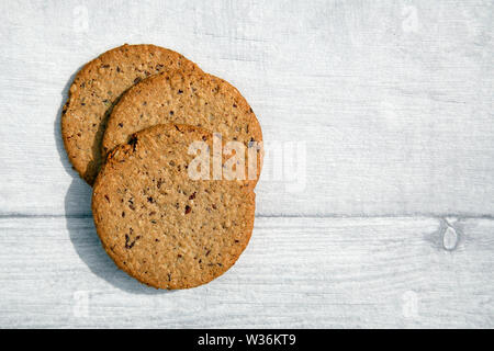 Gluten Free Oatcake faite avec les graines de lin et les raisins secs - convient pour les végétaliens. Isolé sur une table rustique. Banque D'Images