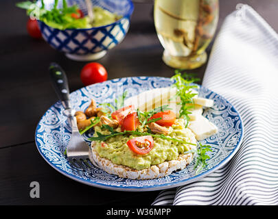 Toasts avocat sain pour le petit déjeuner ou le déjeuner, d'avocat, roquette, tomates, noix de cajou, fromage feta et le poivre. Des sandwiches végétariens. Banque D'Images