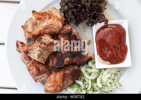 Morceaux de brochettes avec du ketchup et les oignons sur une plaque Banque D'Images