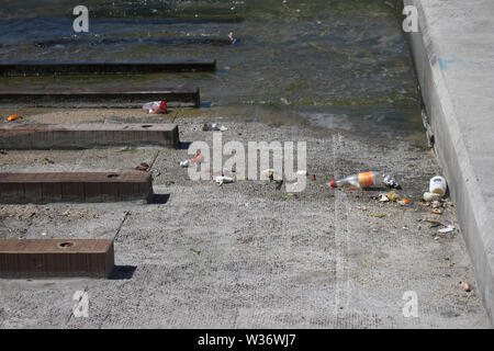 Les déchets dans le secteur de port sur le chemin de béton à l'eau. Bouteille en plastique, écorce d'orange et plusieurs autres pièces en plastique. Banque D'Images