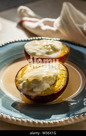 Pêches au four avec du yaourt grec et le miel / les nectarines. Dessert bio. Banque D'Images