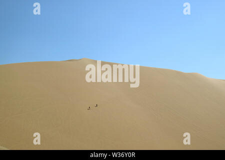 Deux personnes s'amusant sur la grande dune de sable de désert Huacachina, région Ica, Pérou, Amérique du Sud Banque D'Images