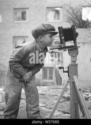 Garçon dans les années 1940. Un enfant curieux s'intéresse à une caméra montée sur un trépied. Suède 1945. Kristoffersson Ref N107-5 Banque D'Images