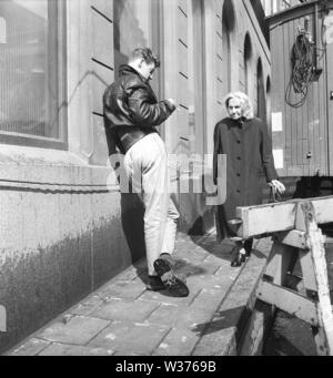 Scène de rue dans les années 50. Une vieille dame est sur le point de passer un jeune homme qui se tient à sa manière. Elle marche avec précaution pour éviter toute difficulté, mais plus probablement le jeune homme est un type bien. La Suède 1958 Kristoffersson ref CA29-6 Banque D'Images