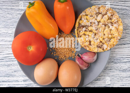 L'ail, poivrons, tomates, graines de lin, les oeufs de poule, tortilla de maïs sur une plaque gris, sur une table en bois. Concept de régime Banque D'Images