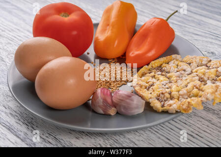 L'ail, poivrons, tomates, graines de lin, les oeufs de poule, tortilla de maïs sur une plaque gris, sur une table en bois. Concept de régime Banque D'Images