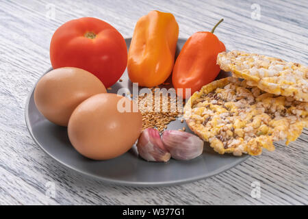 L'ail, poivrons, tomates, graines de lin, les oeufs de poule, tortilla de maïs sur une plaque gris, sur une table en bois. Concept de régime Banque D'Images