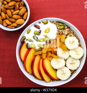 Le petit-déjeuner végétarien sain Bol de fruits et noix muesli avec du yaourt et Golden sultanines Banque D'Images