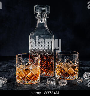 Les verres de whisky avec un carré carafe sur une pierre noire. Banque D'Images