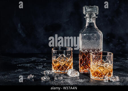 Les verres de whisky avec un carré carafe sur une pierre noire. Banque D'Images