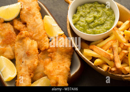 Filets de tacaud frits, Trisopterus luscus, qui ont été enrobées de pâte et frits à la maison pour prendre un poisson et frites au dîner. Le tacaud Banque D'Images