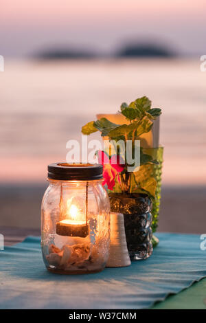 Bougie sur une table dans un restaurant avec vue sur le coucher du soleil sur l'île de Koh Chang, Thaïlande Banque D'Images