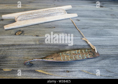 S'attaquer à l'ancienne pour clignotant vertical les poissons prédateurs. Forgé cuivre spinner et le tambour en bois avec corde sur fond rustique. Banque D'Images