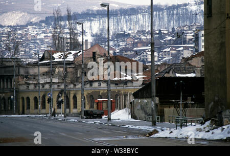 2 avril 1993 pendant le siège de Sarajevo : dans un paysage de l'holocauste et les bâtiments détruits une femme court à travers Hiseta Street où elle est dans le collimateur de la sniper. La coquille d'une voiture se trouve sur son toit sur la chaussée. Banque D'Images