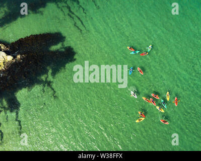Une photographie aérienne de kayaks de mer colorés sur une eau claire comme du cristal sur l'océan Banque D'Images