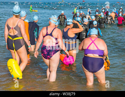 Bournemouth, Dorset, UK. Le 13 juillet, 2019. Pier à Pier sunset nager où les nageurs brave la Manche piscine à partir de Bournemouth à 1.4 km Boscombe piers dans défi de l'eau ouverte, la levée de fonds pour la fondation du Cœur, la BHF. Le premier coucher du soleil baigner à Bournemouth où les nageurs ont 2 heures pour terminer l'nager puis vous détendre sur la plage pour profiter du coucher du soleil, devant deux autres Pier à Pier nage qui doit avoir lieu demain au cours de la journée - des milliers de marcheurs dans les trois périodes. Une belle soirée pour l'ensoleillé chaud nager. Credit : Carolyn Jenkins/Alamy Live News Banque D'Images