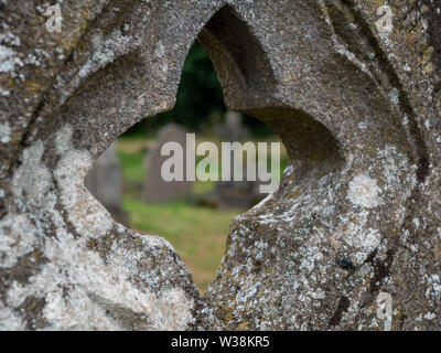 Regardant à travers le trou en forme de croix d'une pierre tombale dans le cimetière Route Histon, Cambridge Banque D'Images