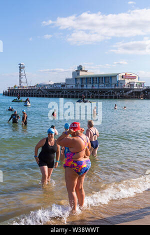 Bournemouth, Dorset UK. 13 juillet 2019. Pier à Pier sunset nager où les nageurs brave la Manche piscine à partir de Bournemouth à 1.4 km Boscombe piers dans défi de l'eau ouverte, la levée de fonds pour la fondation du Cœur, la BHF. Le premier coucher du soleil baigner à Bournemouth où les nageurs ont 2 heures pour terminer l'nager puis vous détendre sur la plage pour profiter du coucher du soleil, devant deux autres Pier à Pier nage qui doit avoir lieu demain au cours de la journée - des milliers de marcheurs dans les trois périodes. Une belle soirée pour l'ensoleillé chaud nager. Credit : Carolyn Jenkins/Alamy Live News Banque D'Images