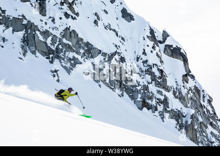 Skieur dans l'arrière-pays de l'Alaska's Talkeetna Mountains. C'est le broyage de poudreuse sous les falaises de granite recouvert de neige fraîche. Banque D'Images