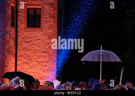 Chemnitz, Allemagne. Le 13 juillet, 2019. Les visiteurs de l'open-air show MDR 'Die Schlager des Sommers sont debout avec parasols dans la cour du château Klaffenbach. En raison d'un violent orage l'enregistrement a dû être interrompu pendant un certain temps. Credit : Sebastian Willnow/dpa-Zentralbild/dpa/Alamy Live News Banque D'Images