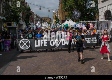 Londres, Royaume-Uni. 13 juillet 2019. Rébellion d'extinction de mars à Londres Hackney Downs à travers champs Hackney central comme un rappel de l'action urgente est nécessaire pour éviter l'extinction à l'échelle mondiale. Avant le mois de mars il y avait un spectacle de danse et de méditation sur la catastrophe climatique à venir. Derrière la bannière principale clé Dan's Band a joué pour un enterrement traditionnel de la Nouvelle Orléans et a été suivi par des squelettes géants représentant des animaux déjà disparues ou menacées, un cercueil, des abeilles géantes, des gens avec des drapeaux et d'un groupe de samba. Peter Marshall/Alamy Live News Banque D'Images