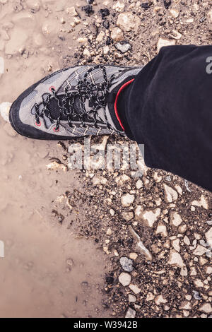 Jambe mâle portant des chaussures de randonnée sportive chaussures dans la boue et l'eau. Chaussures de trekking pour Sport de montagne Sentier pédestre. Banque D'Images