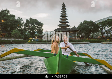 Jeune beau couple pagayer sur un bateau en bois à Pura Ulun Danu Bratan, Bali - Touristes explorer Bali Banque D'Images